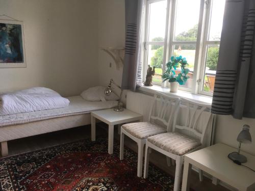 a bedroom with a bed and two chairs and a window at Hostel California in Hinge