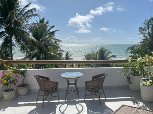 a balcony with chairs and a table and the ocean at Casa Turmalina in Japaratinga