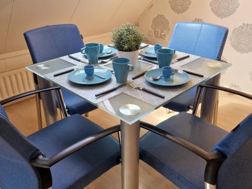a table with blue chairs and plates on it at VakantieStudio 88 in Kamperland