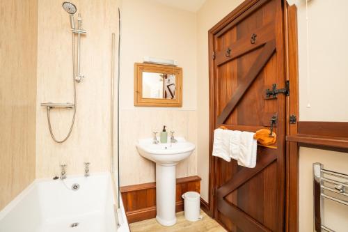 a bathroom with a sink and a bath tub and a toilet at Ystumgwern Luxury Barn Conversions in Dyffryn