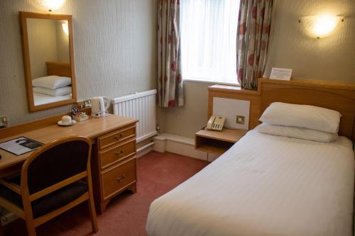 a bedroom with a bed and a desk and a mirror at Alma Lodge Hotel in Stockport