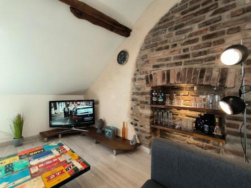 - un salon avec une télévision et un mur en briques dans l'établissement Ideal longue durée centre ville, à Pau