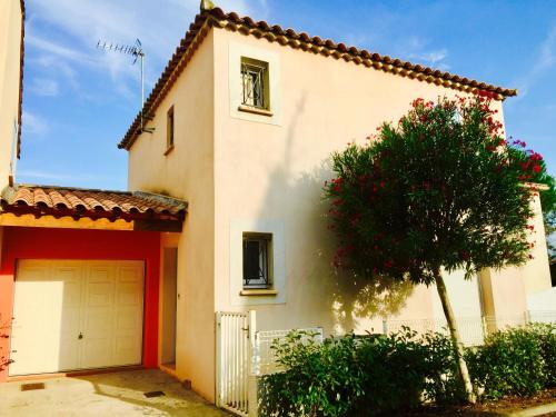 ein weißes Haus mit einer Garage und einem Baum in der Unterkunft Bastide Saint Vincent in Le Grau-dʼAgde