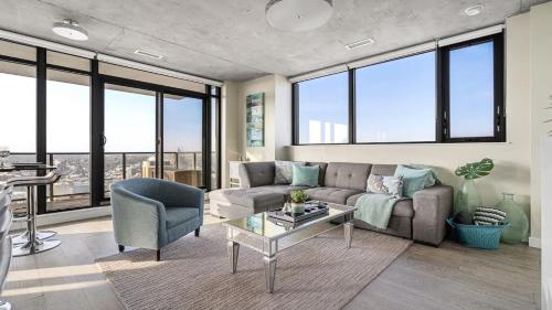 a living room with a couch and a table and windows at Executive Sky LUX - 2 BD 2BA Views Pool Patio & Gym in Calgary
