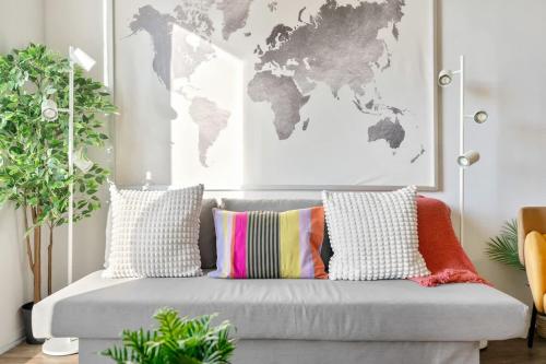 a living room with a gray couch with pillows and a map at Eminence Sleek Studio City View in Edmonton