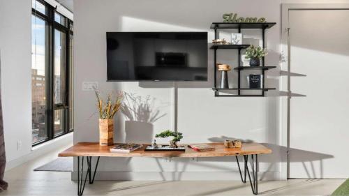 a living room with a table and a tv at Miso 2 BD - Skyline View Patio Gym Pool & AC in Calgary
