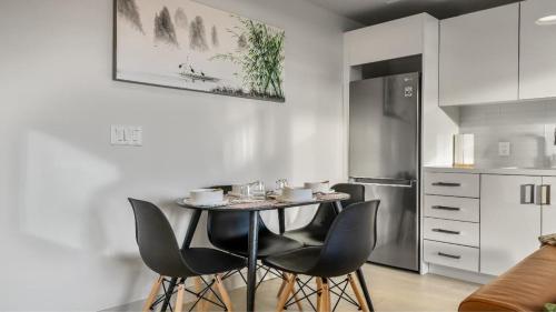 a kitchen with a table with chairs and a refrigerator at Miso 2 BD - Skyline View Patio Gym Pool & AC in Calgary