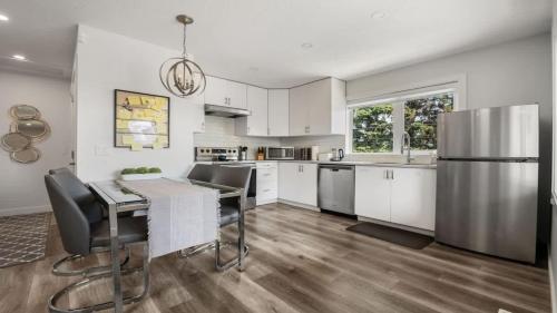 a kitchen with a table and a stainless steel refrigerator at Winston Suite 2BR 1BA - Carriage Suite with Garage in Calgary