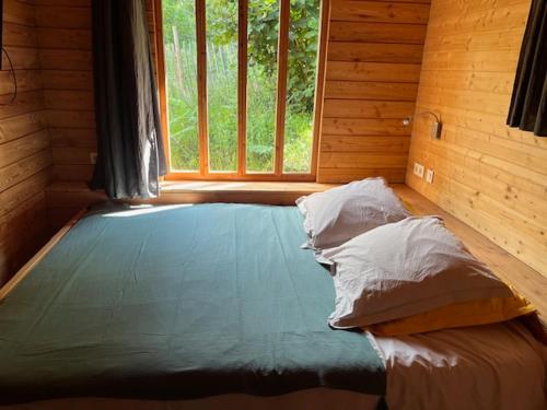 Ce lit se trouve dans une chambre en bois dotée d'une fenêtre. dans l'établissement Les gîtes de Sainte Croix, à Sainte-Croix-Vallée-Française