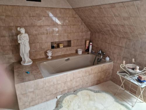 - une salle de bains pourvue d'une baignoire avec une statue de femme dans l'établissement Ti Bras, à Ploubazlanec