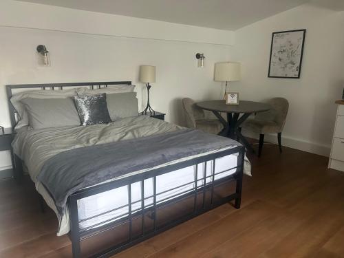 a bedroom with a bed and a table with chairs at Spacious studio with free EV recharge overnight in Watford
