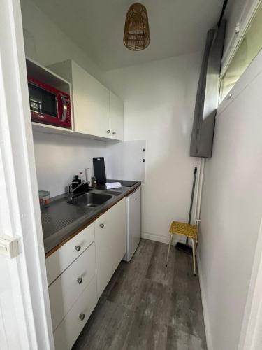 une petite cuisine avec un évier et un micro-ondes dans l'établissement Studio et terrasse près de Paris, à Suresnes