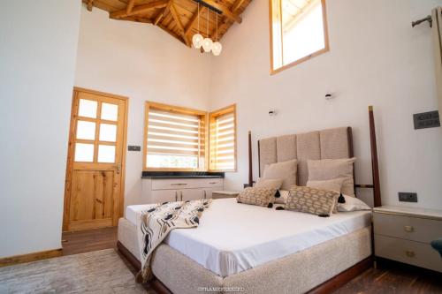 a bedroom with a large bed in a room with windows at Kailasha villaa in Rānīkhet