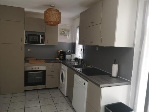 une cuisine avec un évier et un lave-vaisselle dans l'établissement Maison avec jardin clos dans residence, à Gruissan