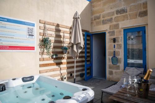 a jacuzzi tub in a patio with a table and an umbrella at Mandera's Boutique Suites & Dorms in Valletta