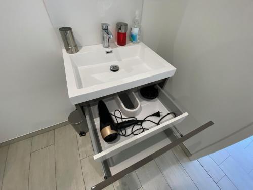 La salle de bains est pourvue d'un lavabo blanc et d'une étagère. dans l'établissement Cabine de la plage, à Bréhal