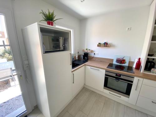 une cuisine avec un réfrigérateur blanc et un évier dans l'établissement Cabine de la plage, à Bréhal