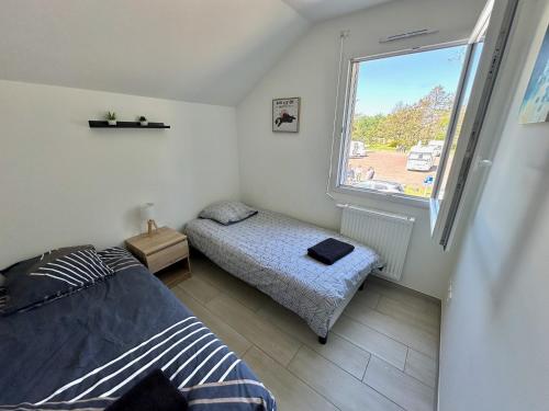 une chambre avec deux lits et une fenêtre dans l'établissement Cabine de la plage, à Bréhal