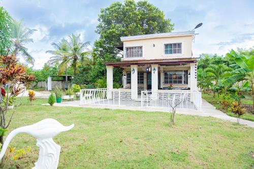 a white house with a porch in a yard at Rancho Juliana in Villas del Mar