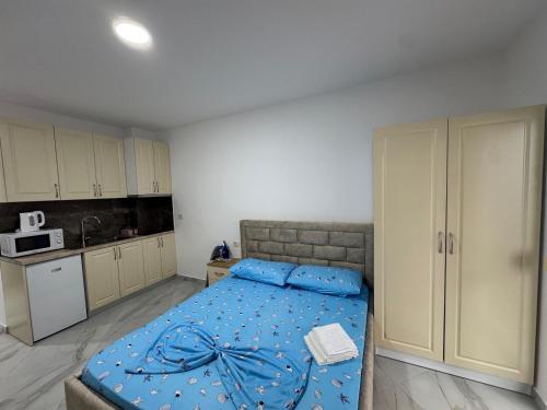 una camera da letto con un letto blu e una cucina di Djonis Rooms a Shëngjin