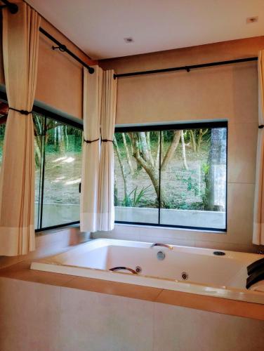 a large bath tub in a room with a window at Cabanas Privativas com Jacuzzi, Cozinha, Churrasqueira e Decoração - Sitio Pauletto in Jarinu
