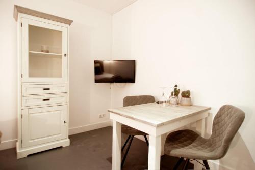 a white dining room table with two chairs and a tv at Two Tulips Inn Dutch Retreat in Hillegom