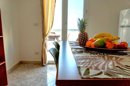 a plate of fruit on a table with a view of the ocean at DV holiday home in Isola delle Femmine