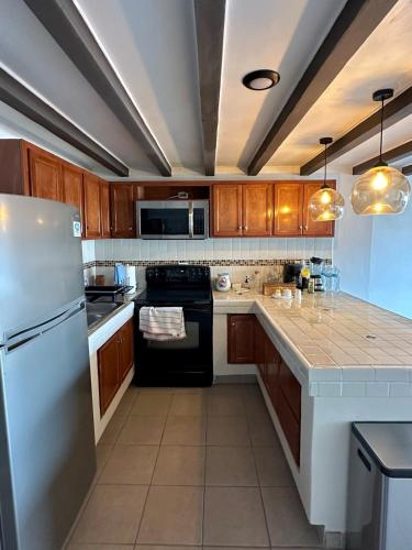 a kitchen with wooden cabinets and a white refrigerator at Rocky Suite, close to everything in Ensenada