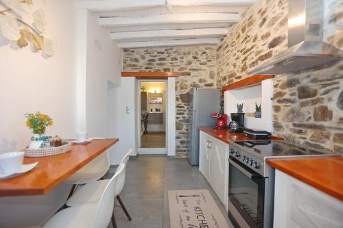 a kitchen with white counters and a stone wall at Thealos view in Ermoupoli