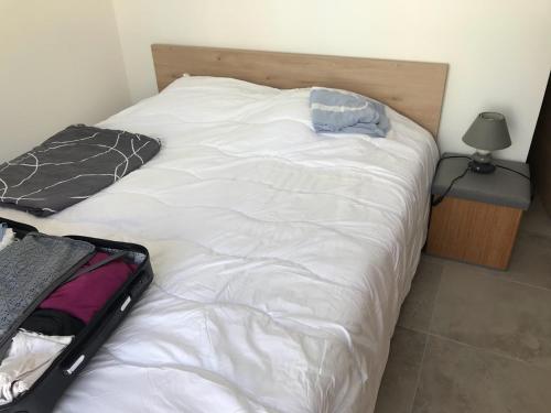- un grand lit blanc avec une valise ouverte dans l'établissement Location Vacances en Coeur de ville - Vue sur Mer - Tout confort, à Calvi