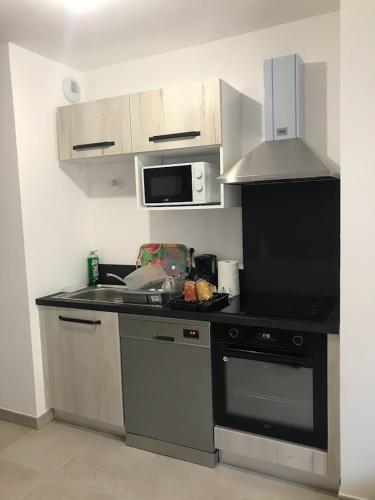 une cuisine avec une cuisinière et un micro-ondes dans l'établissement Location Vacances en Coeur de ville - Vue sur Mer - Tout confort, à Calvi