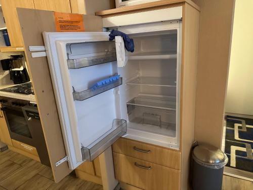 an empty refrigerator with its door open in a kitchen at Moderne und komfortable Appartements im Ferienpark Hahnenklee in Hahnenklee-Bockswiese