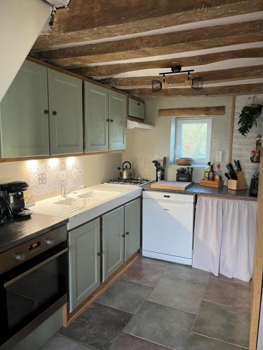 une cuisine avec des appareils blancs et un plafond en bois dans l'établissement A la campagne, à Saint-Calez-en-Saosnois