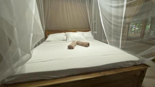 a bed with a teddy bear laying on it at RURAL CLAY HOUSE Hiriketiya in Hiriketiya