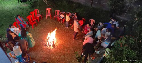 a group of people standing around a camp fire at View Point Stay in Madikeri