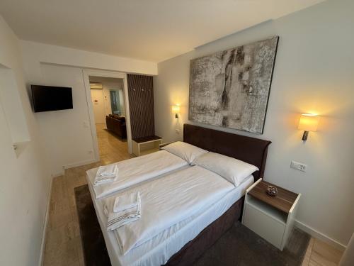 a bedroom with a large bed with a painting on the wall at San Carlo Luxury Apartments in Lugano