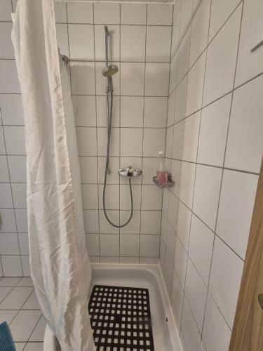 a shower in a white tiled bathroom with a shower curtain at Chambre cosy et chaleureuse chez Soso in Châtel-Saint-Denis
