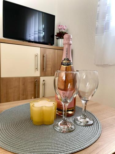 a bottle of champagne and two wine glasses on a table at Викендица Братунац in Bratunac