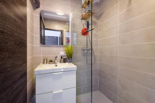 une salle de bain blanche avec un lavabo et un miroir dans l'établissement Appartement calme avec terrasse et climatisation, à Nice