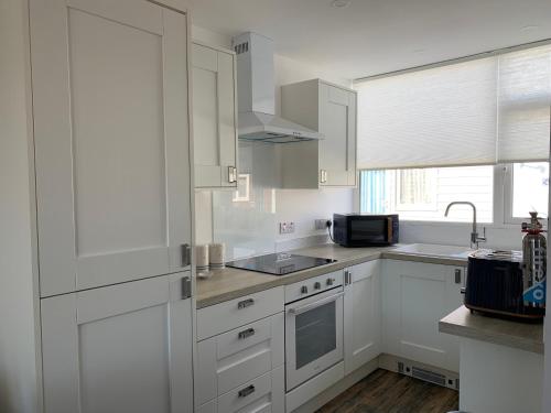 a white kitchen with white cabinets and a sink at Beach Buoys holiday chalet Close to the dog friendly beach in Bridlington