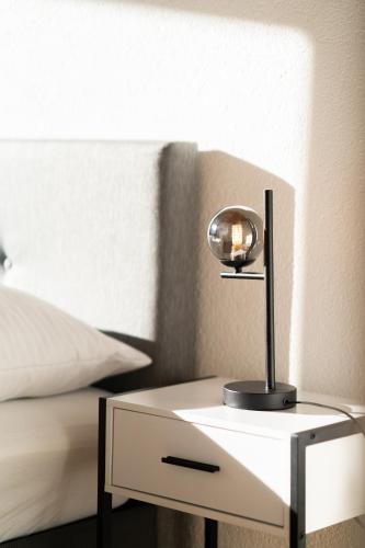 a small white table with a lamp on it next to a bed at homy Alpine Deluxe Chalet in St Anton im Montafon in Sankt Anton im Montafon