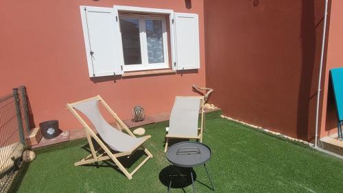 2 chaises et une table sur une terrasse avec pelouse dans l'établissement Grand T2 et jardin proche plages, à Lecci
