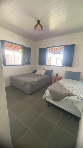 two beds in a room with two windows at Morada Vento dos Lençóis in Santo Amaro