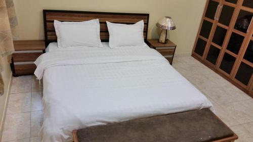a bedroom with a large bed with white sheets at Bahget Eljouf Furnished Apartment in Sakakah