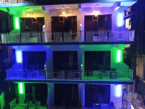 a building with green and blue lights on it at Hotel Hillora Mcleodganj in McLeod Ganj