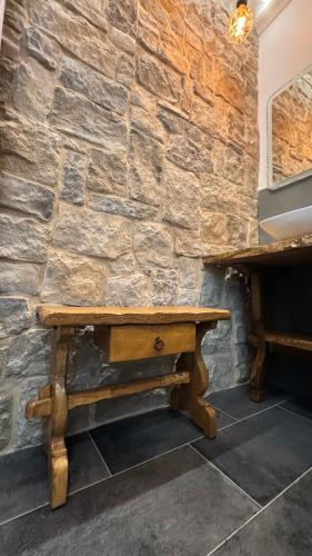 a wooden bench in front of a stone wall at MENTORE MAISON PRESTiGE in Noceto