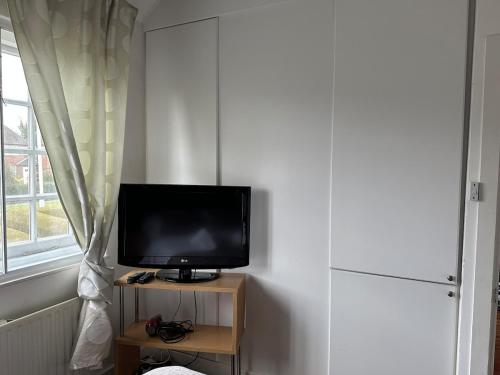 a television sitting on a table next to a window at Cosy 2-Bed Retreat in Hampstead in London