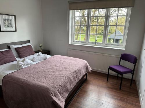 a bedroom with a bed and a chair and a window at Cosy 2-Bed Retreat in Hampstead in London