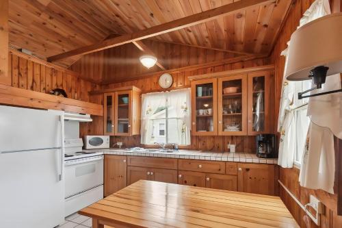 a kitchen with wooden cabinets and a wooden table at Sunnyside Combined 12BR 5BA Lakefront Retreat in Lincoln Junction