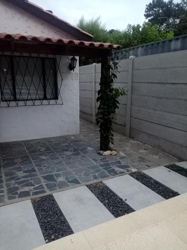 a patio with a tree in the corner of a house at Casa con piscina climatizada para 6 personas en Parque del plata in Parque del Plata